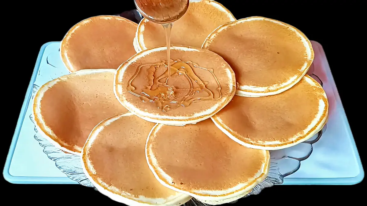 Stack of golden pancakes with honey drizzled on top