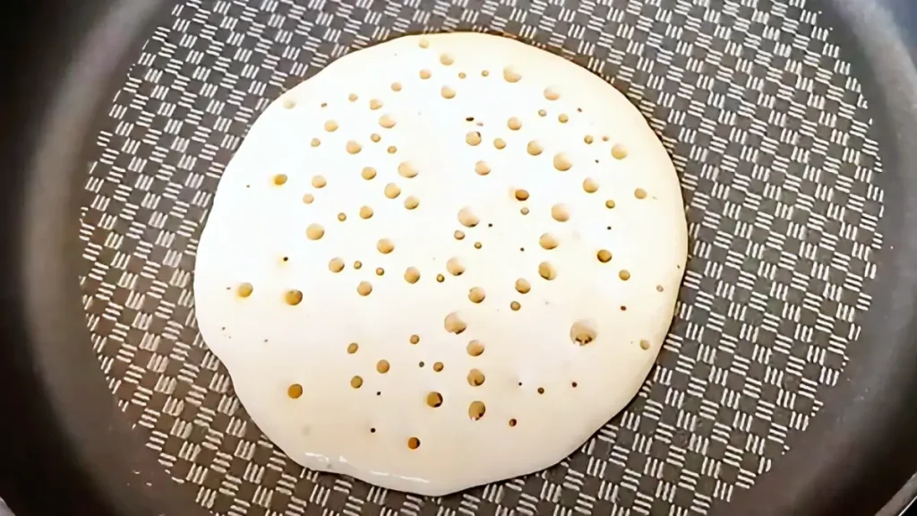 Close-up of golden pancakes cooking in a pan for breakfast